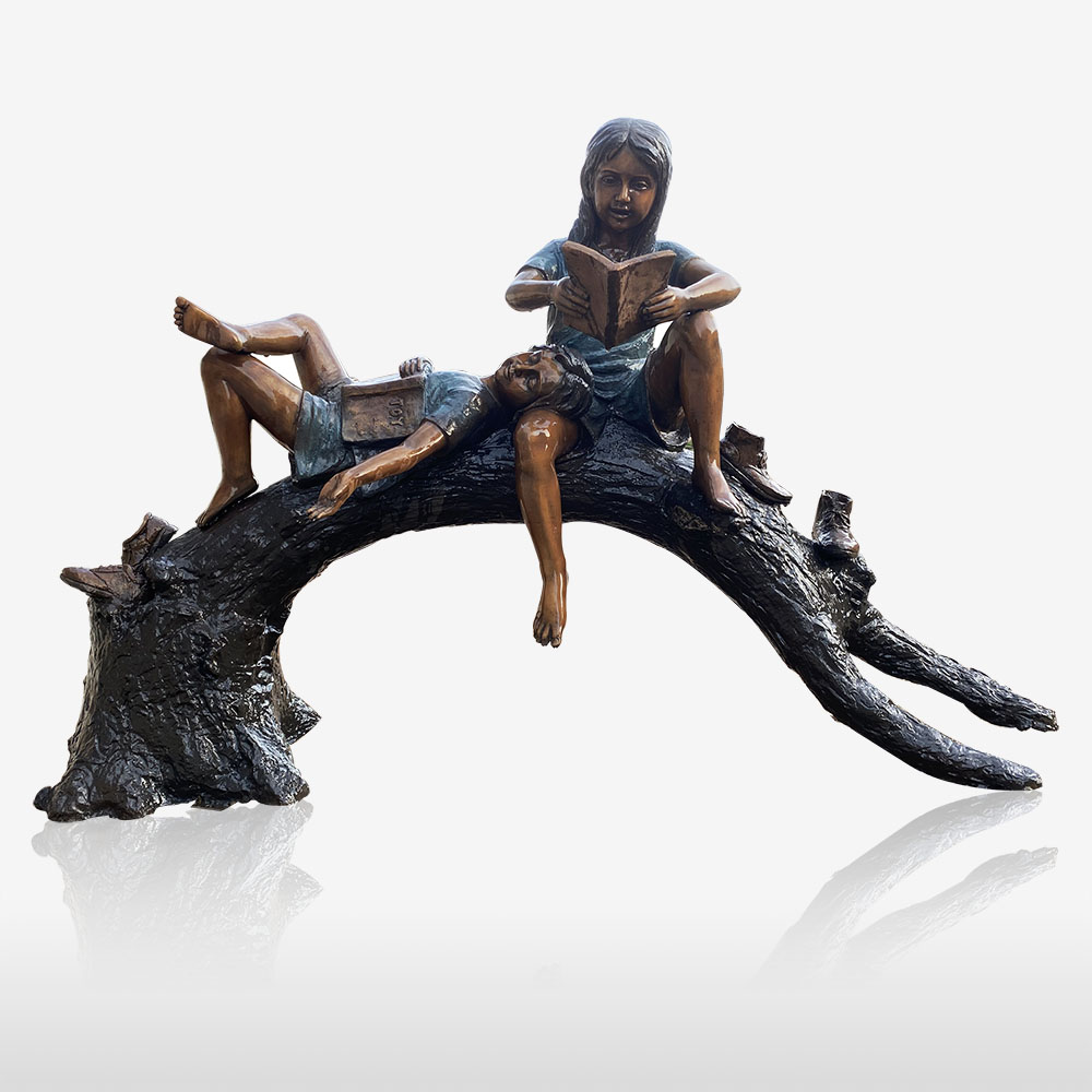 Outdoor bronze statues of kids reading on a tree